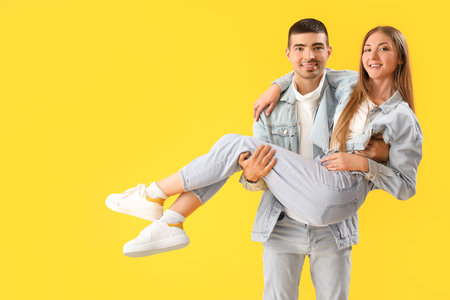 Fashionable young couple in autumn clothes on yellow backgroundの写真素材
