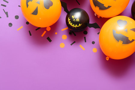 Funny Halloween balloons and confetti on lilac backgroundの写真素材
