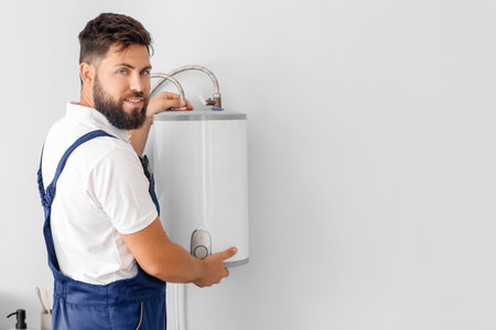 Male plumber installing boiler in bathroomの写真素材