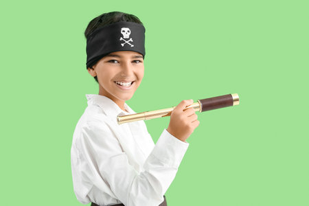 Little boy dressed as pirate with spyglass on green backgroundの写真素材