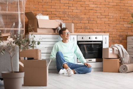 Young man sitting in the kitchen on moving day