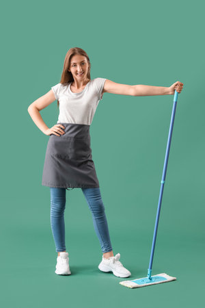 Young woman with mop on green backgroundの写真素材