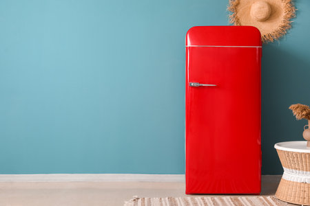 Stylish retro fridge and straw hat on blue wallの写真素材