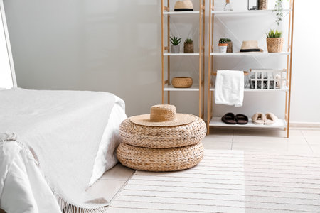 Rattan poufs with hat in cozy bedroomの写真素材