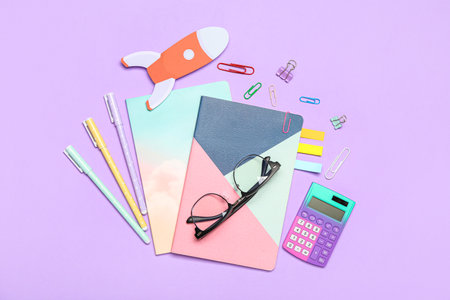 Paper rocket with school stationery and eyeglasses on violet backgroundの写真素材