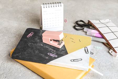 Stapler with stationery supplies on grunge background