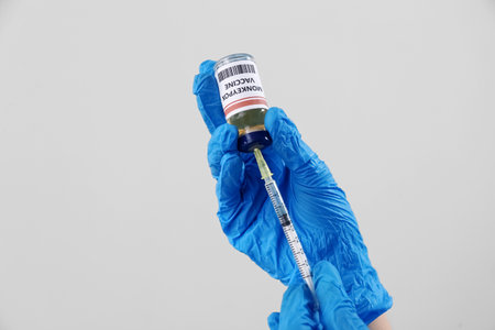 Hands of doctor with monkeypox vaccine and syringe on light backgroundの写真素材
