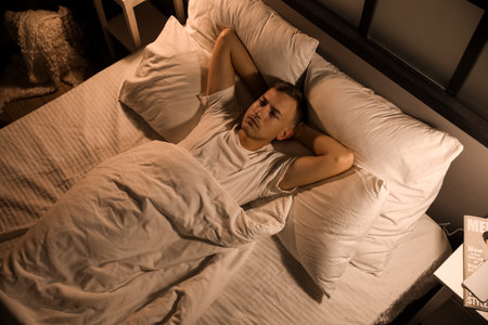Handsome young man lying in bedroom at nightの写真素材