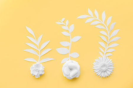 Paper flowers with leaves on yellow background