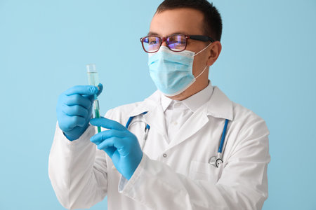 Doctor with ampule and syringe on light blue backgroundの写真素材