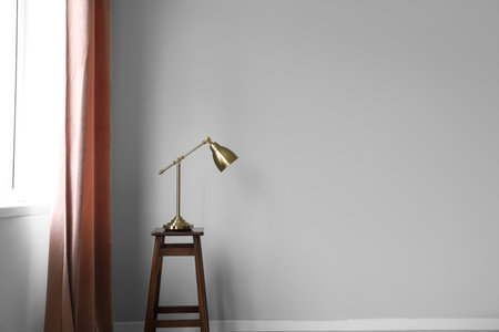 Golden lamp on stool near red curtain in roomの写真素材