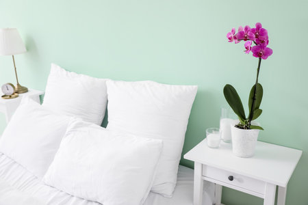 Beautiful orchid flower and candles on table near bedの写真素材