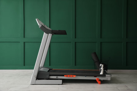 Modern treadmill near green wall