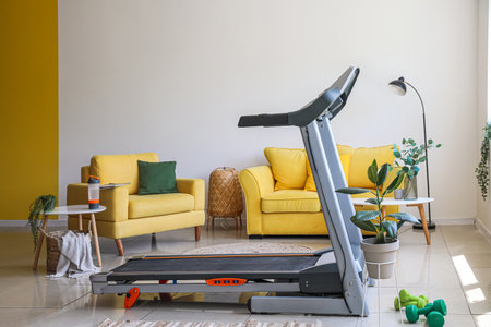 Interior of light living room with treadmill, sofa and armchairの写真素材