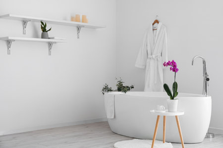 Interior of light room with modern bathtub and table with orchid flowerの写真素材