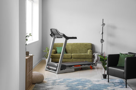 Interior of light living room with treadmill and sofaの写真素材