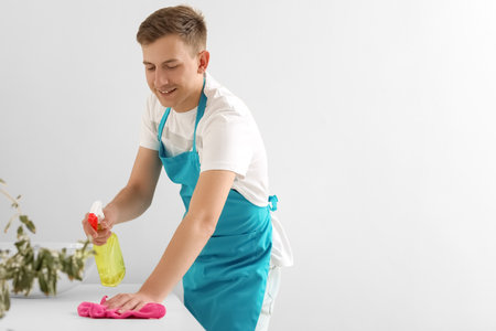 Young man cleaning table with rag in bathroom