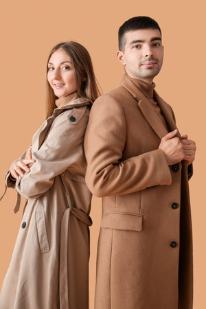 Fashionable young couple in autumn clothes on beige backgroundの写真素材