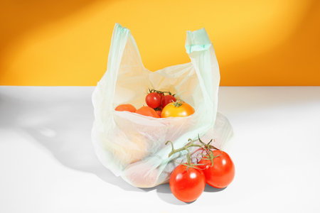 Bag with fresh tomatoes on tableの写真素材