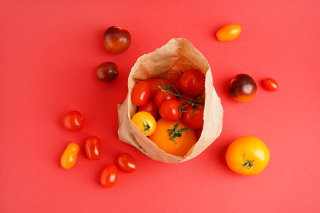 Paper bag with fresh tomatoes on color backgroundの写真素材