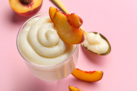 Glass of tasty vanilla pudding with peach on pink background, closeupの写真素材