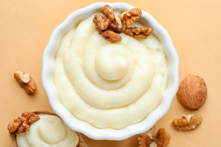 Ramekin of tasty vanilla pudding with walnuts on color background, closeupの写真素材