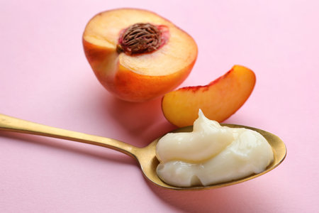 Spoon of tasty vanilla pudding and peach on pink background, closeupの写真素材