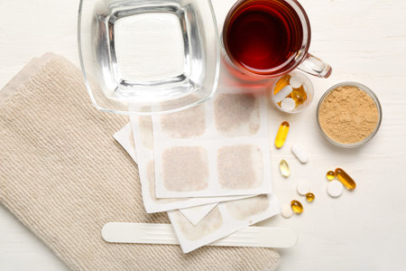 Mustard plasters with pills, bowl of water, tea cup and towel on white wooden backgroundの写真素材