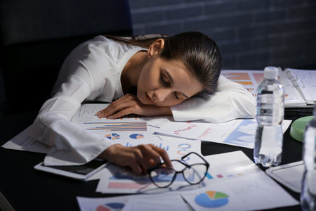 Young businesswoman sleeping in office at nightの写真素材