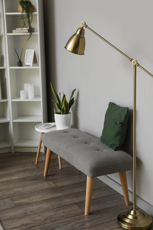 Soft bench with cushion and lamp near light wallの写真素材