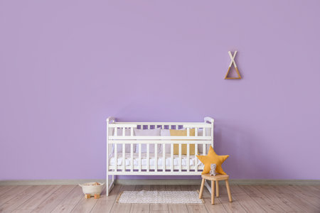 Baby crib, stool and basket with toys near violet wallの写真素材