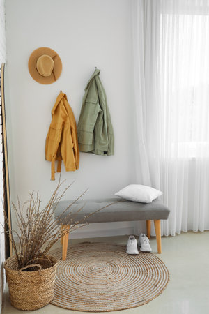 Interior of light hall with soft bench, mirror and jacketsの写真素材