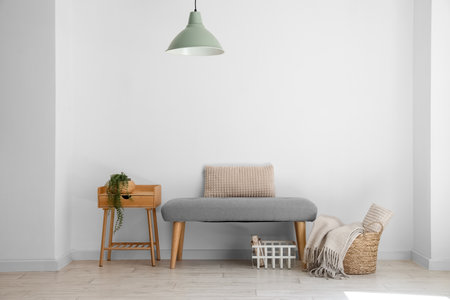 Soft bench with baskets and table near light wallの写真素材