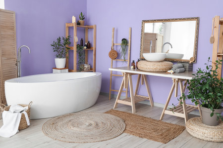 Stylish interior of bathroom with modern bathtub and accessories near color wallの写真素材