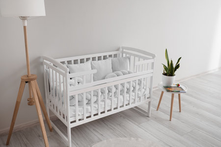 Interior of light nursery with baby crib, lamp and tableの写真素材