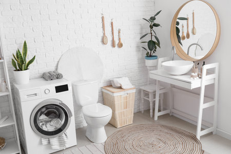 Interior of bathroom with modern washing machine, toilet bowl and sink near white brick wallの写真素材