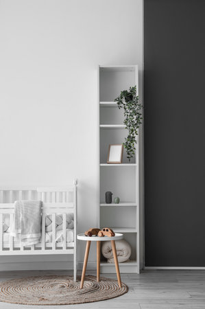 Interior of light nursery with baby crib, table and shelving unitの写真素材