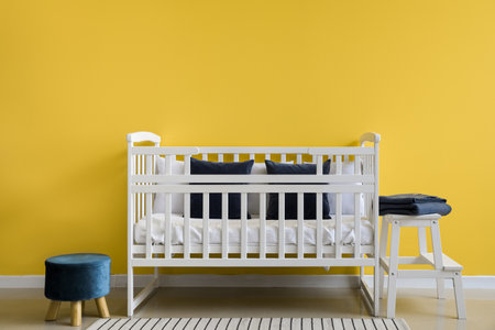 Stylish interior of children's room with comfortable crib near yellow wallの写真素材