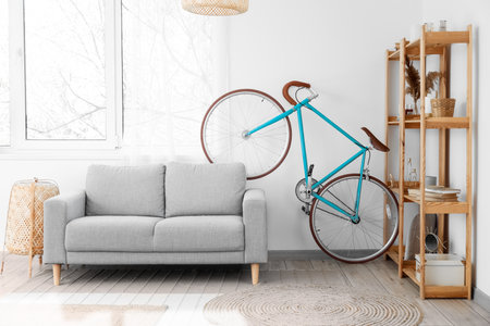 Interior of light living room with bicycle, gray sofa and wooden shelving unitの写真素材