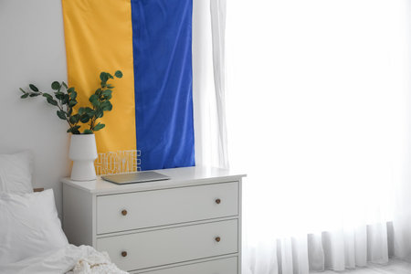 Flag of Ukraine hanging on light wall in modern bedroomの写真素材