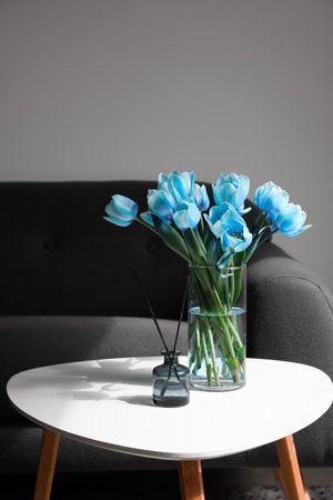 Vase with tulips and reed diffuser on table in living roomの写真素材