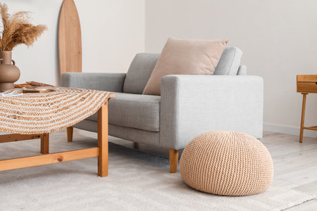 Comfortable sofa, pouf and table near light wall in living roomの写真素材