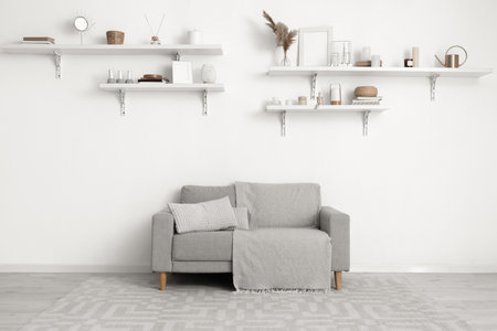 Gray sofa and shelves with decor hanging on light wall