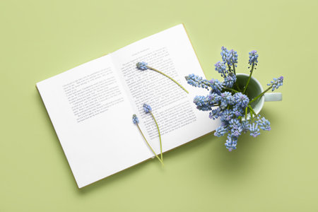 Beautiful Muscari flowers and book on green background, top viewの写真素材