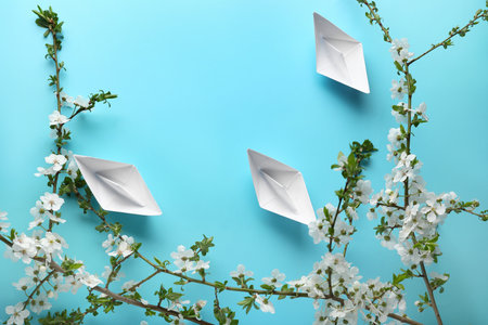 Beautiful blooming spring branches and origami boats on blue backgroundの写真素材