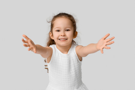 Little girl opening arms for hug on gray backgroundの写真素材