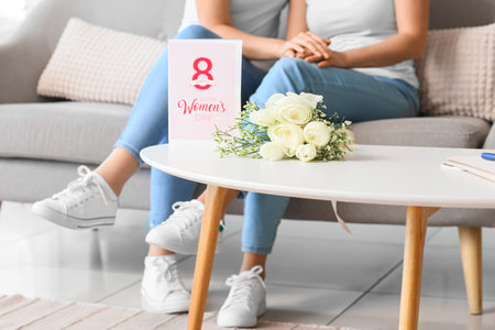Bouquet of flowers and greeting card for International Women's Day on table at homeの写真素材
