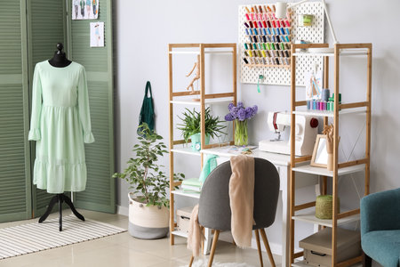 Interior of stylish atelier with tailor's workplace, shelving units and pegboardの写真素材