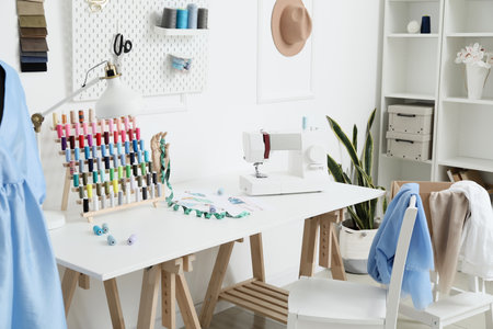 Modern tailor's workplace with sewing machine and thread spools in atelierの写真素材