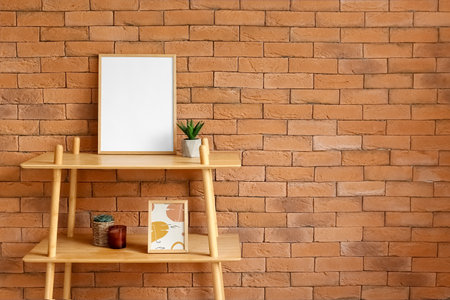 Shelving unit with blank frame and flowerpots near brick wallの写真素材